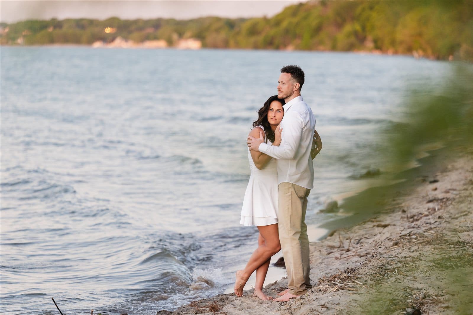 Danielle and Sheldon standing together at the water's edge at golden hour